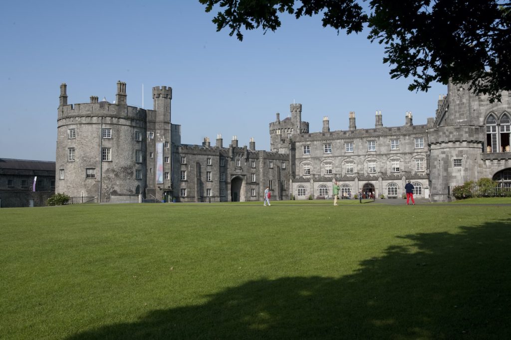 Elegant stone castle hotel with spacious green lawn, inviting guests to explore royal architecture and enjoy serene surroundings.