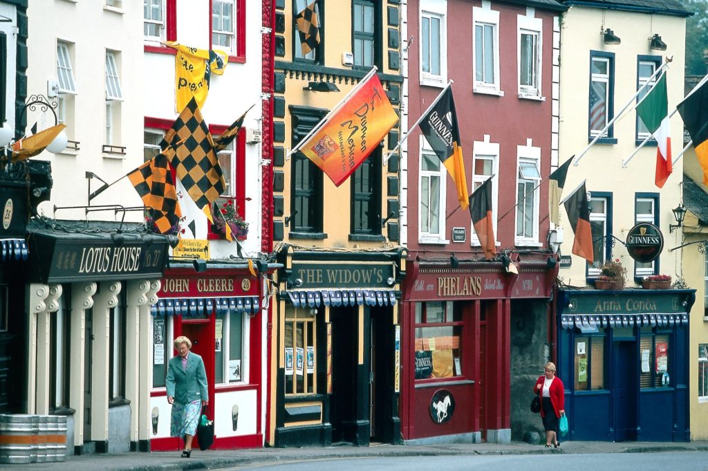 Colourful Irish pub street with vibrant flags, charming facades, and cheerful locals, offering a lively cultural experience.
