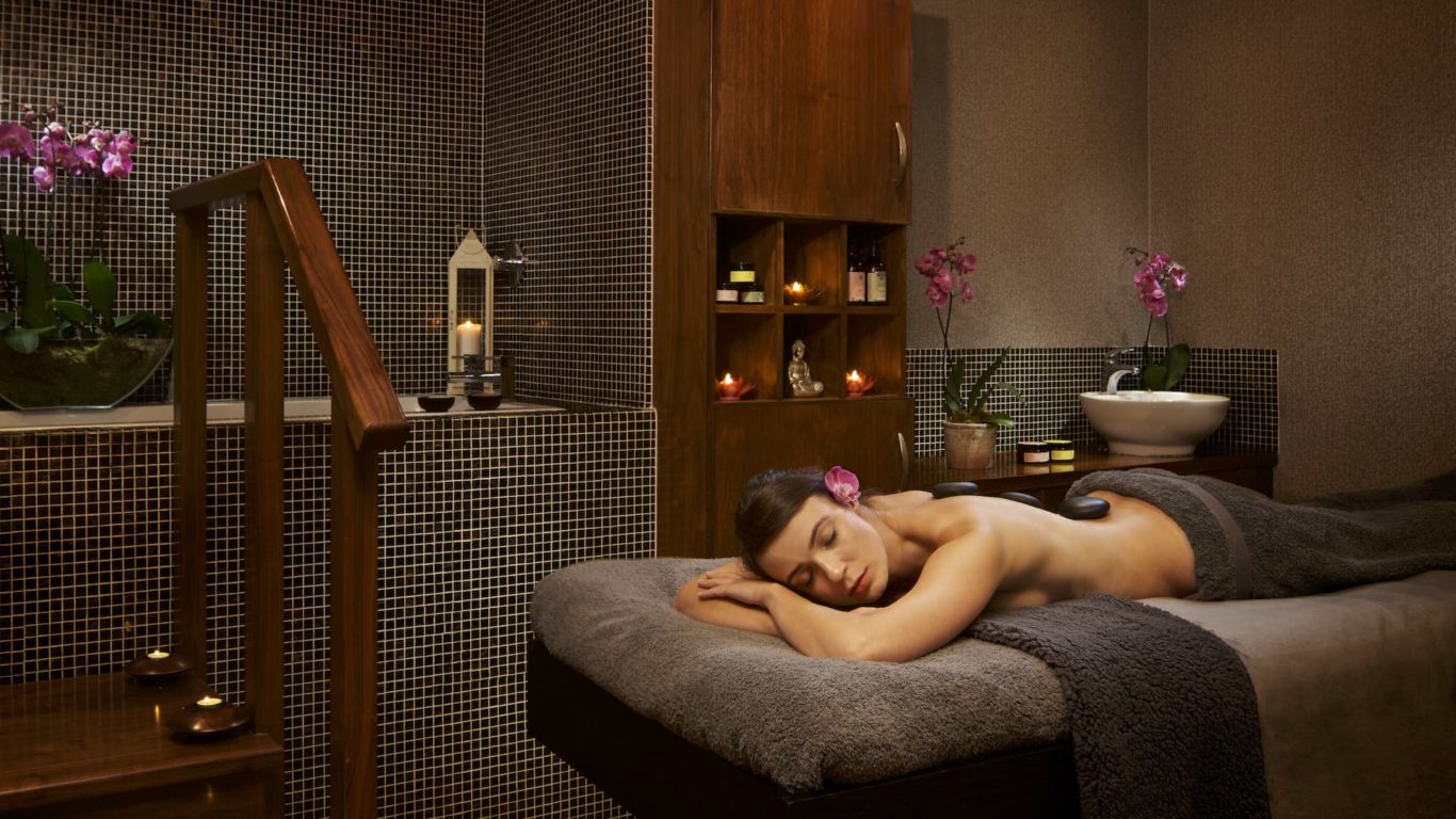 Relaxing spa room with candles, orchids, massage table, offering a serene retreat in a luxurious hotel wellness centre.