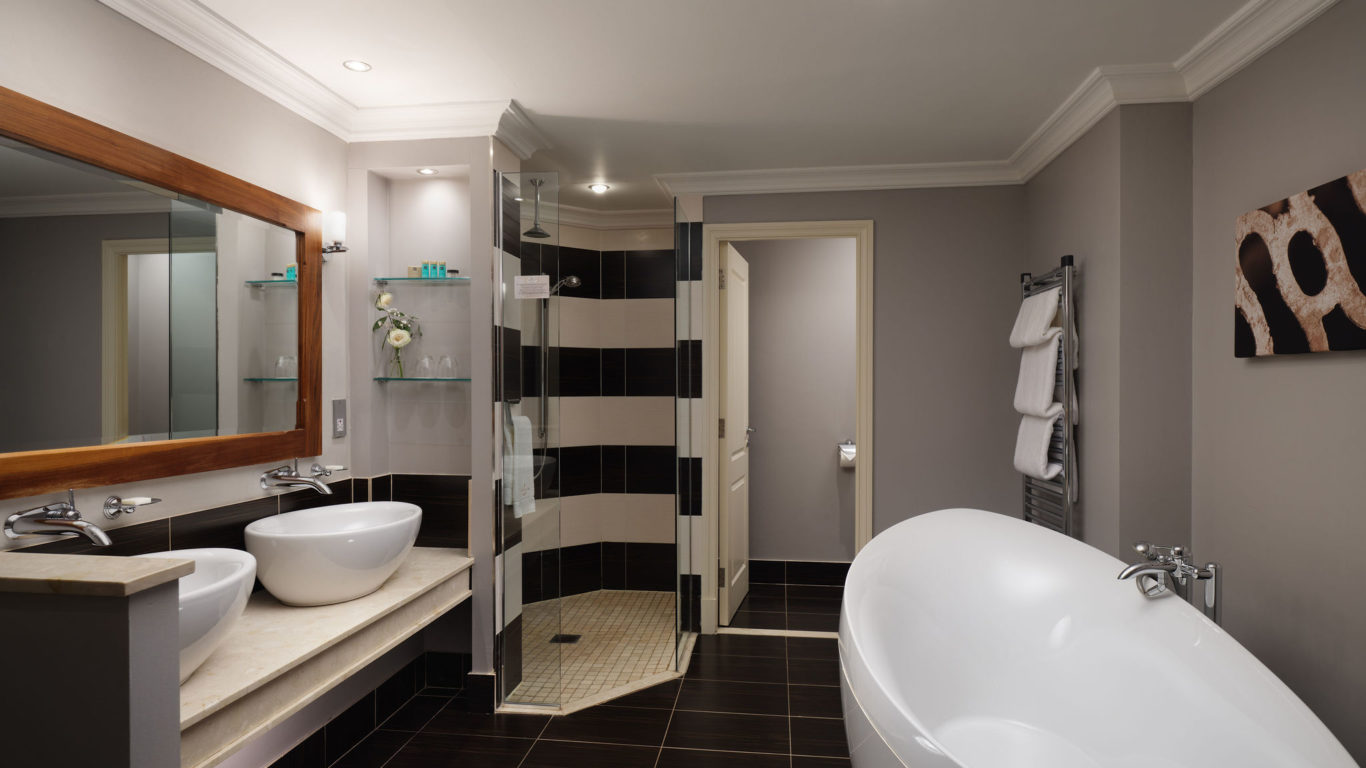 Luxurious hotel bathroom with modern freestanding tub, double sinks, spacious rain shower, elegant decor. Relax in style.