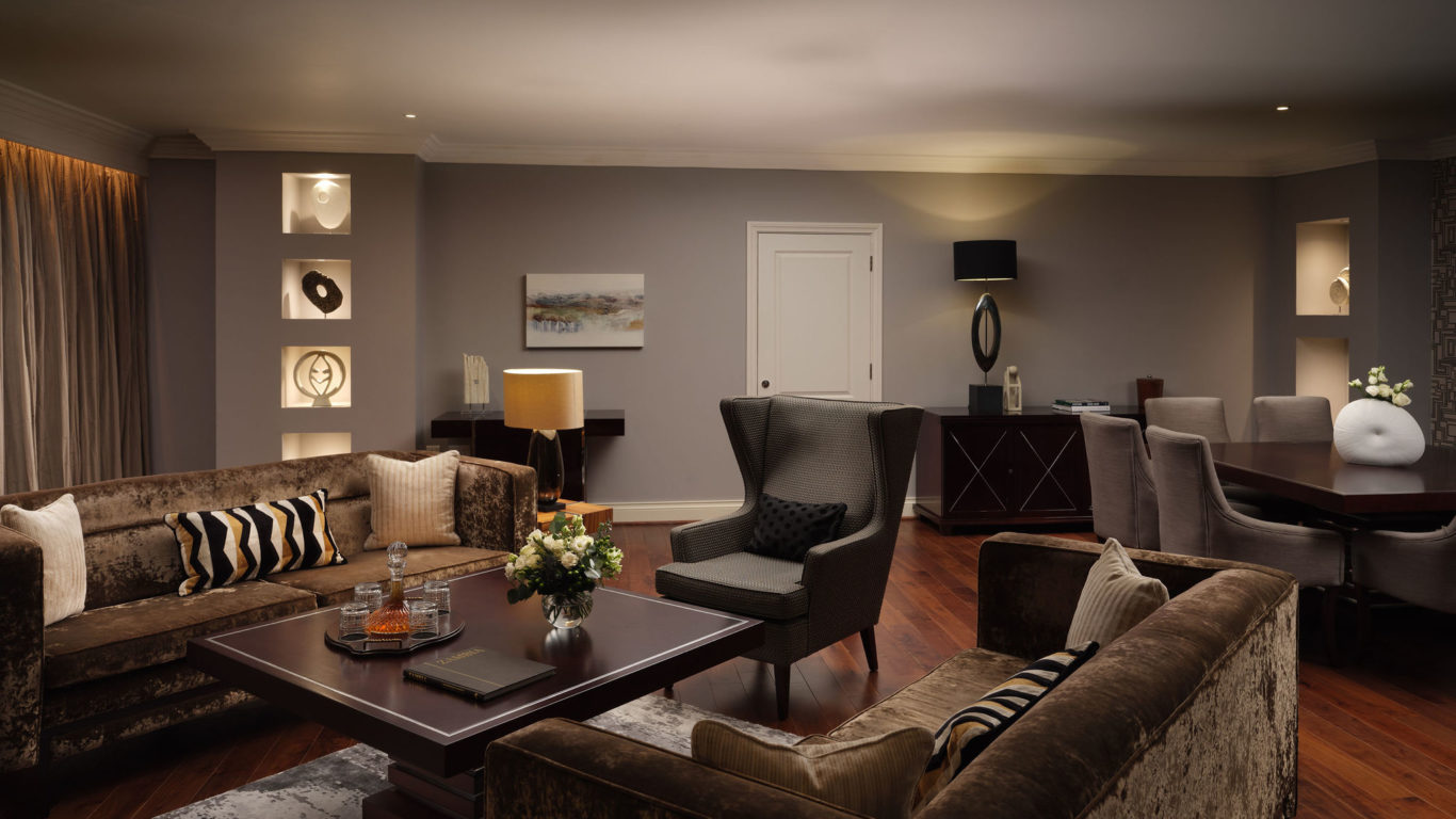 Luxurious hotel suite with plush sofas, elegant decor, and modern lighting, creating a cosy and inviting atmosphere.
