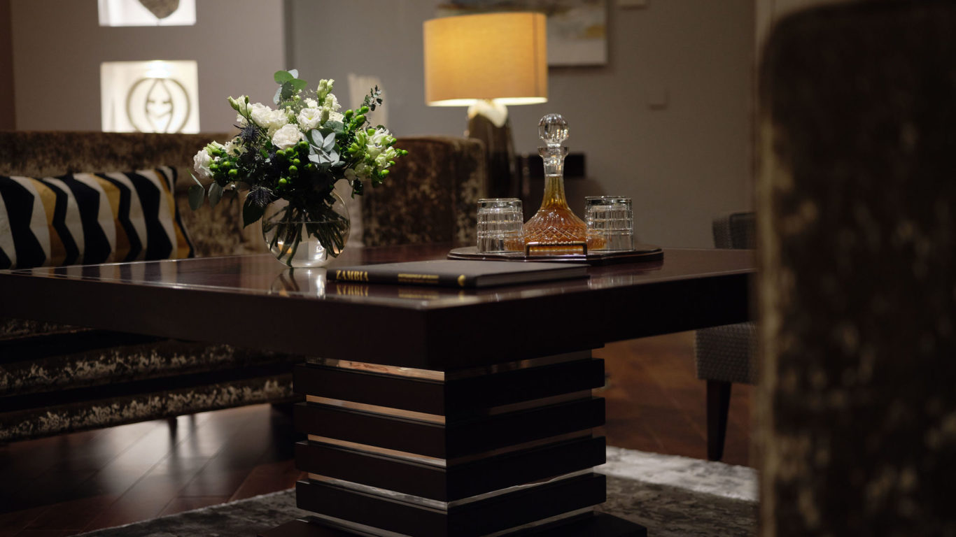 Luxurious hotel lounge with elegant decor, plush seating, floral centrepiece, and ambient lighting for a warm welcome.