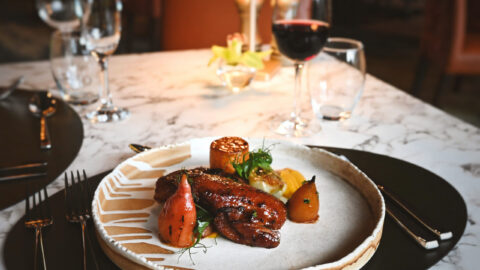 Indulge in gourmet dining at our luxury hotel restaurant, featuring elegantly plated dishes and fine wine on a marble table.