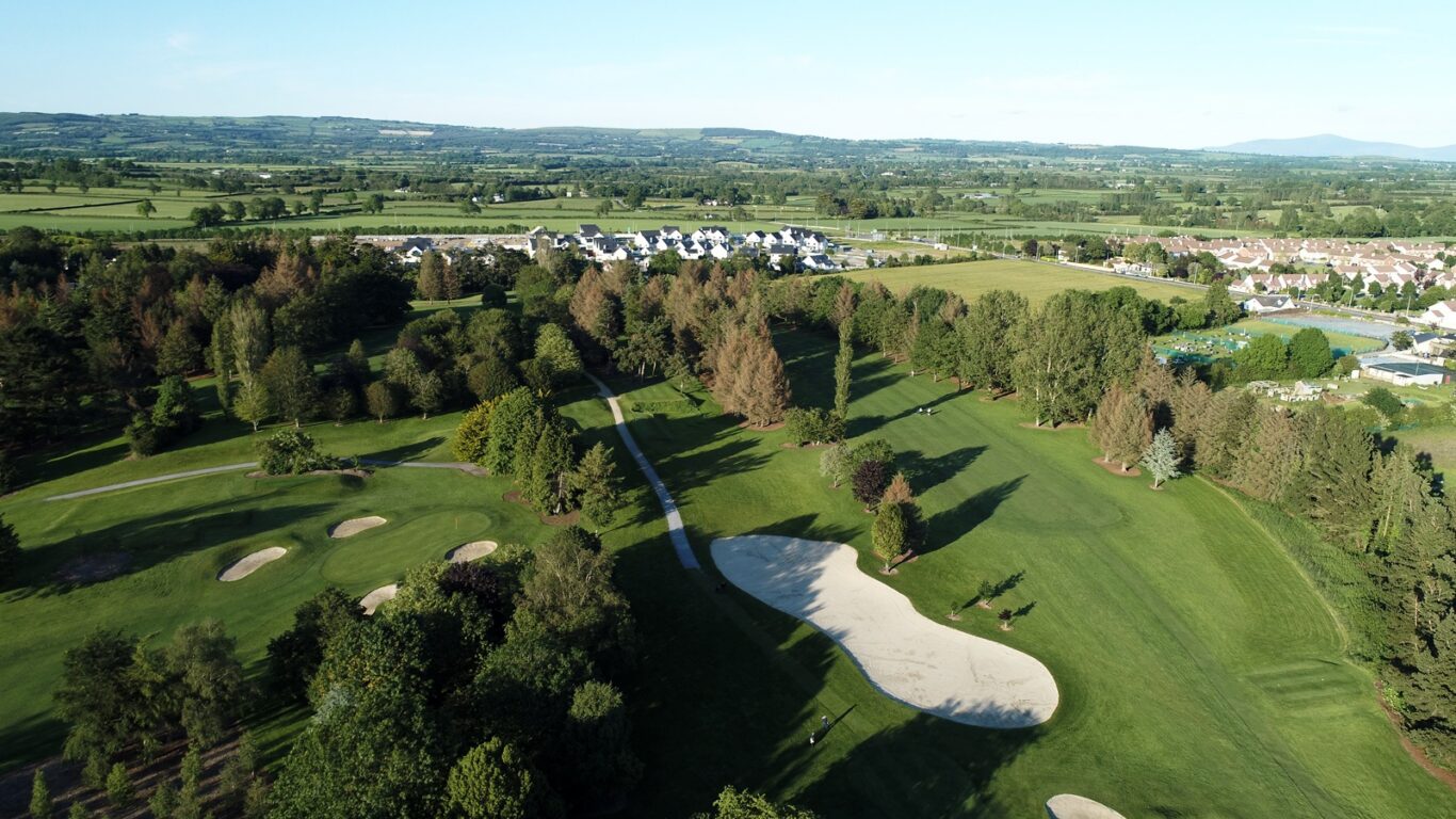 Aerial view of lush hotel golf course, surrounded by scenic countryside and modern accommodations, ideal for relaxation.